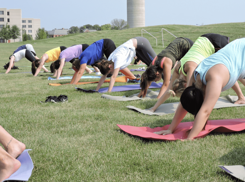 Students managing stress by participating in yoga outside