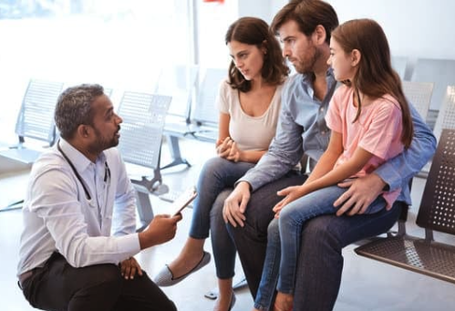 Photo of a physician meeting and speaking with a family to discuss a medical issue. 